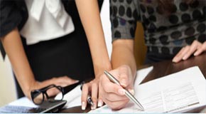 Two people working on an audit at a table verifying rule compliance
